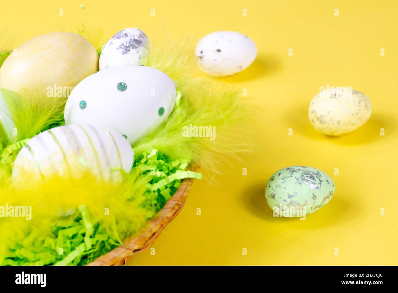Easter nest with eggs and feathers on a yellow background close-up ...