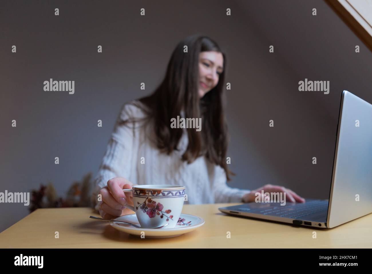 A female hand holding a cup whilst working Stock Photo