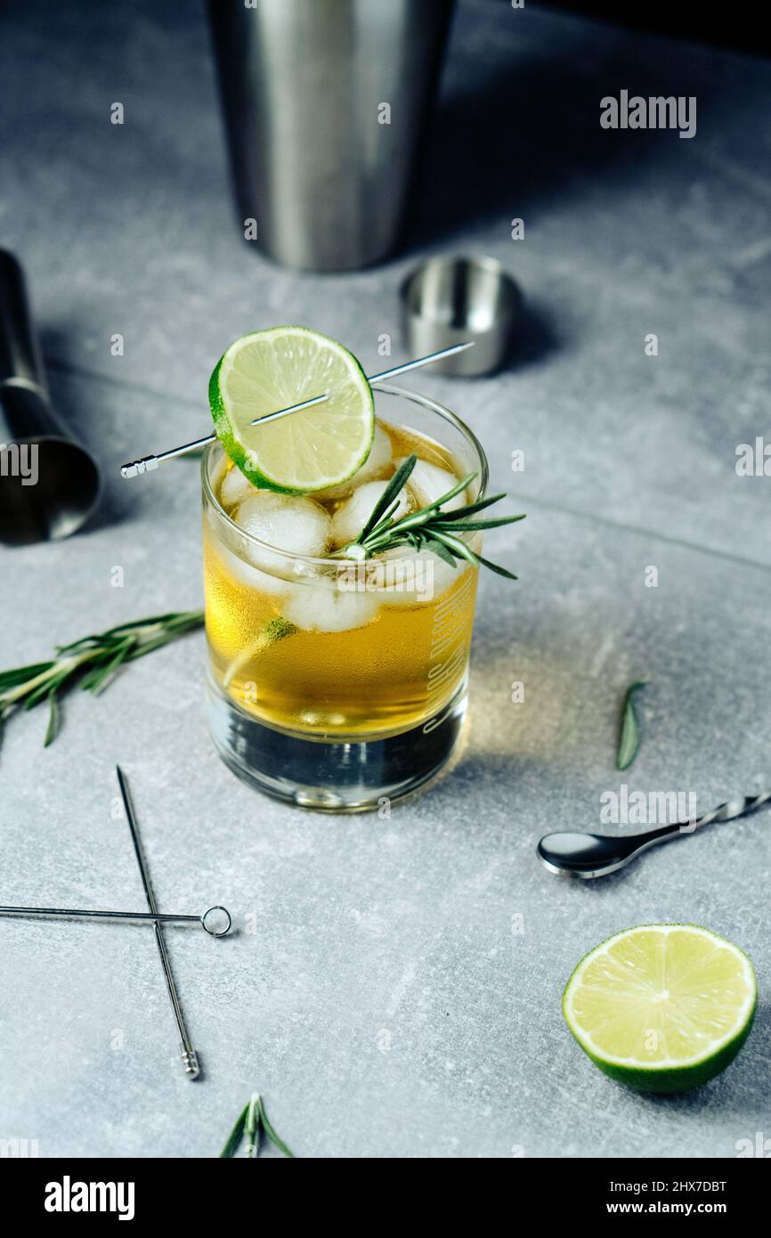 Alcohol cocktail with lime slice rosemary ice and cocktail shaker on