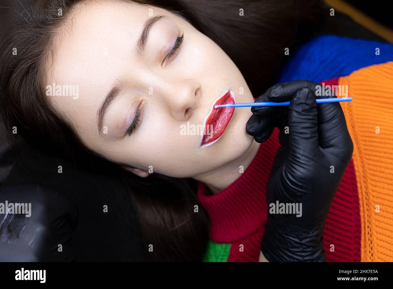 the procedure of permanent lip tattooing with black gloves is to apply