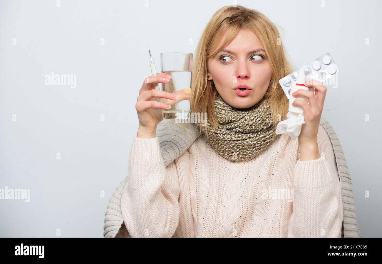 Miracle cure. Cute sick girl taking anti cold pill. Unhealthy woman holding pills and water glass. Medication and increased fluid intake. Ill woman Stock Photo