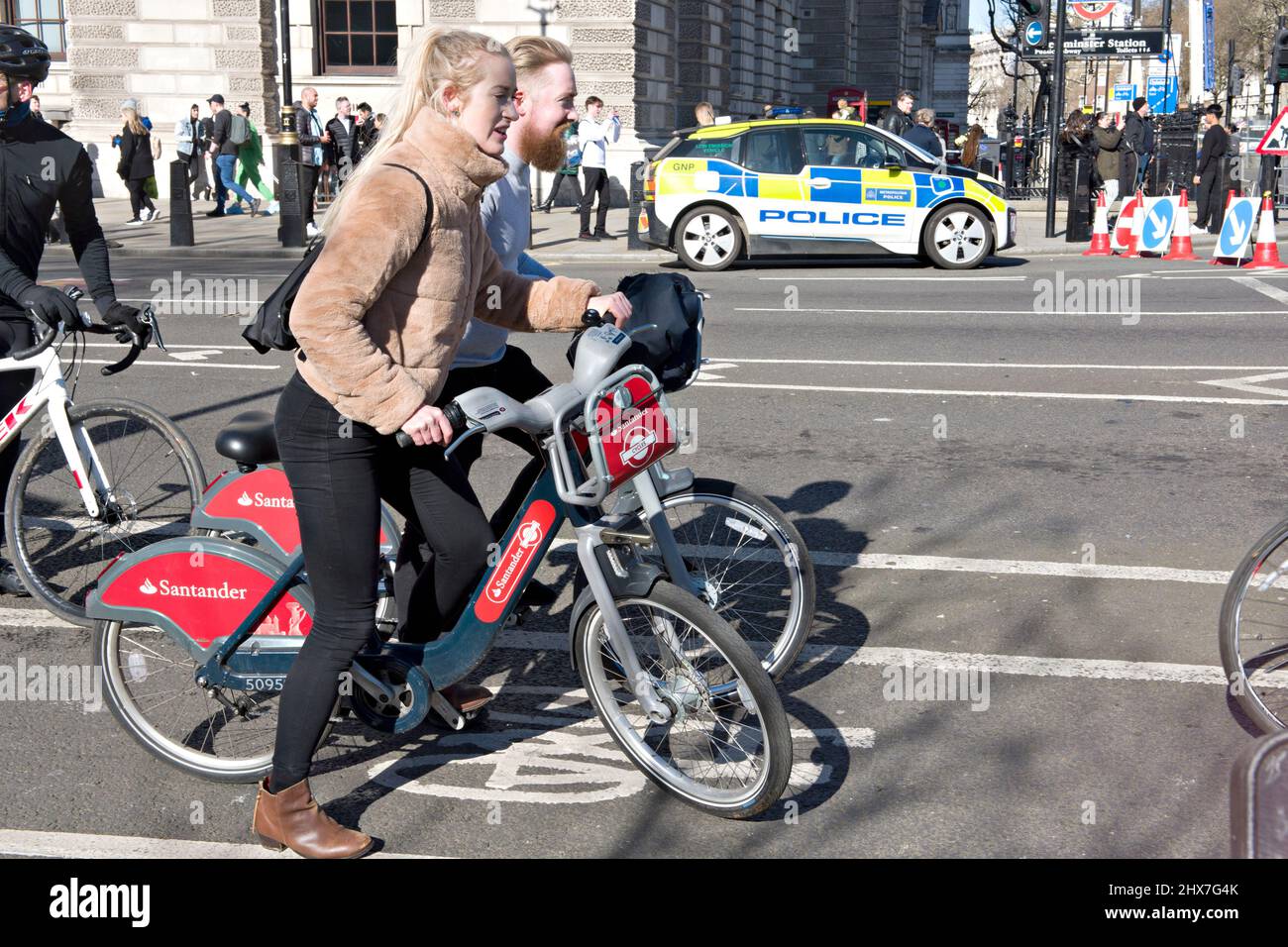 A couple using the bike hire service inLondon. Seen here in Westminster, central London. The bike hire scheme, promoting more green transport, was introduced in 2010; Barclays Bank being the first sponsor, and Santander from 2015. Although generally known as 'Boris bikes, after the London Mayor at the time; the concept was actually first promoted by the previous mayor, Ken Livingtone. Stock Photo