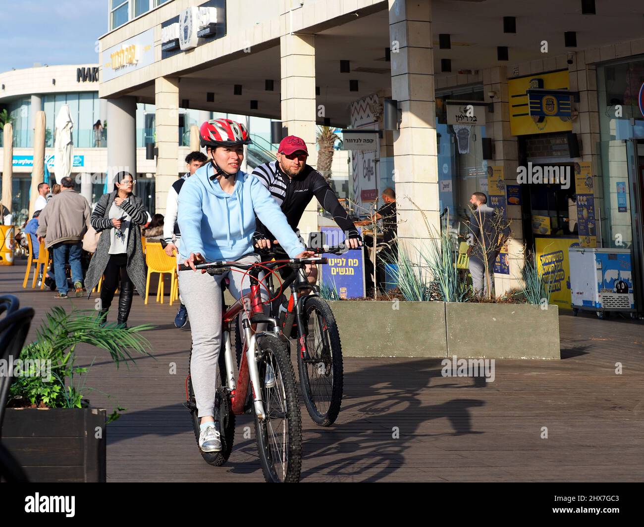 ASHKELON, ISRAEL - MARCH 04, 2022: a guy and a girl ride a bike along the embankment. Stock Photo