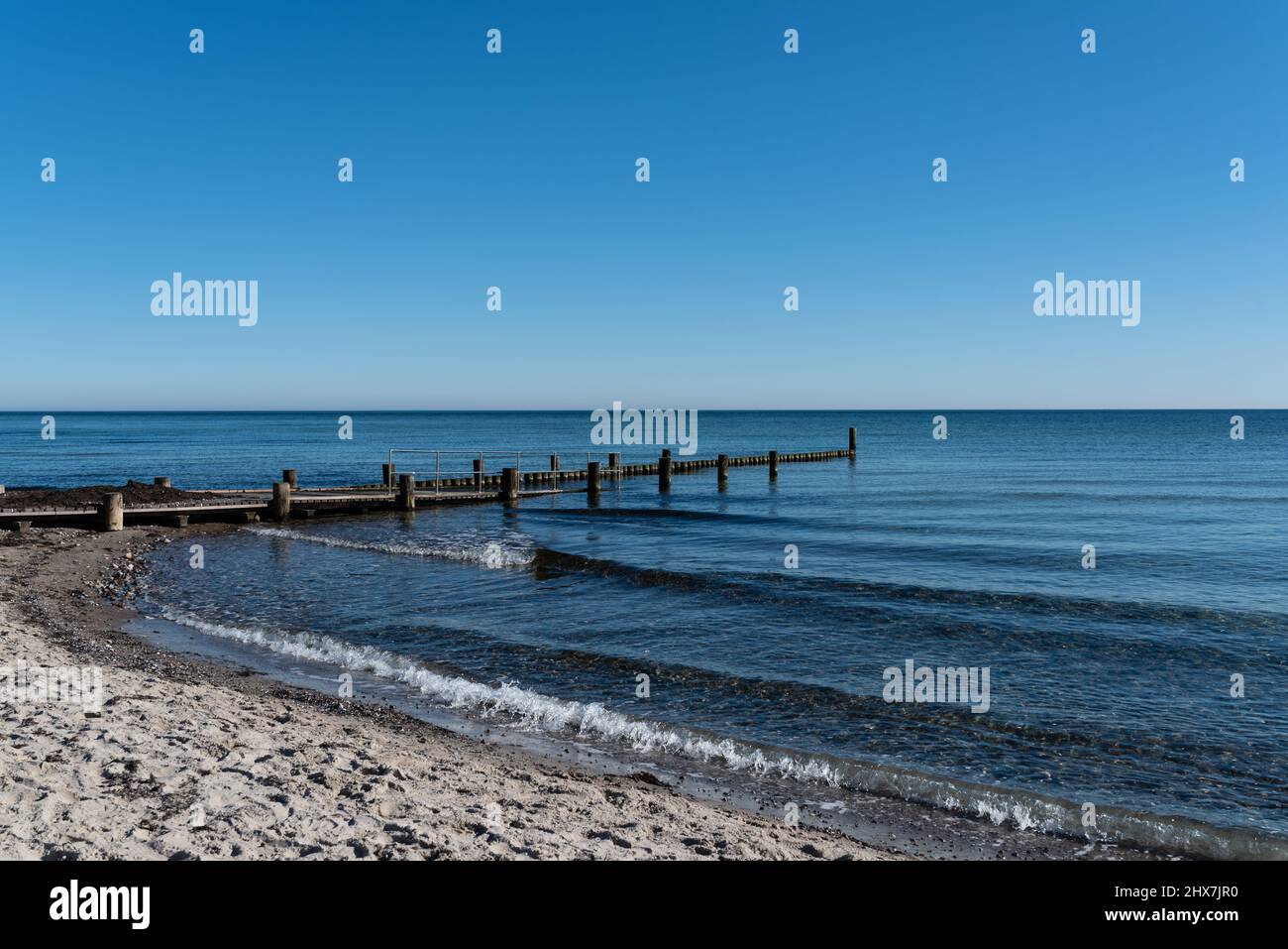 baltic sea sandy beach with bathing jetty and wooden breakwater against clear blue sky Stock Photo