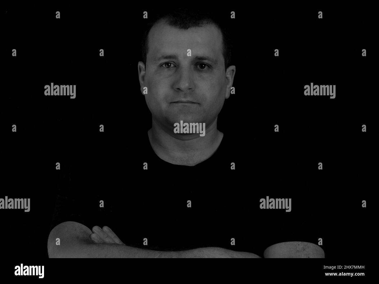Man folded his arms on a black background Stock Photo