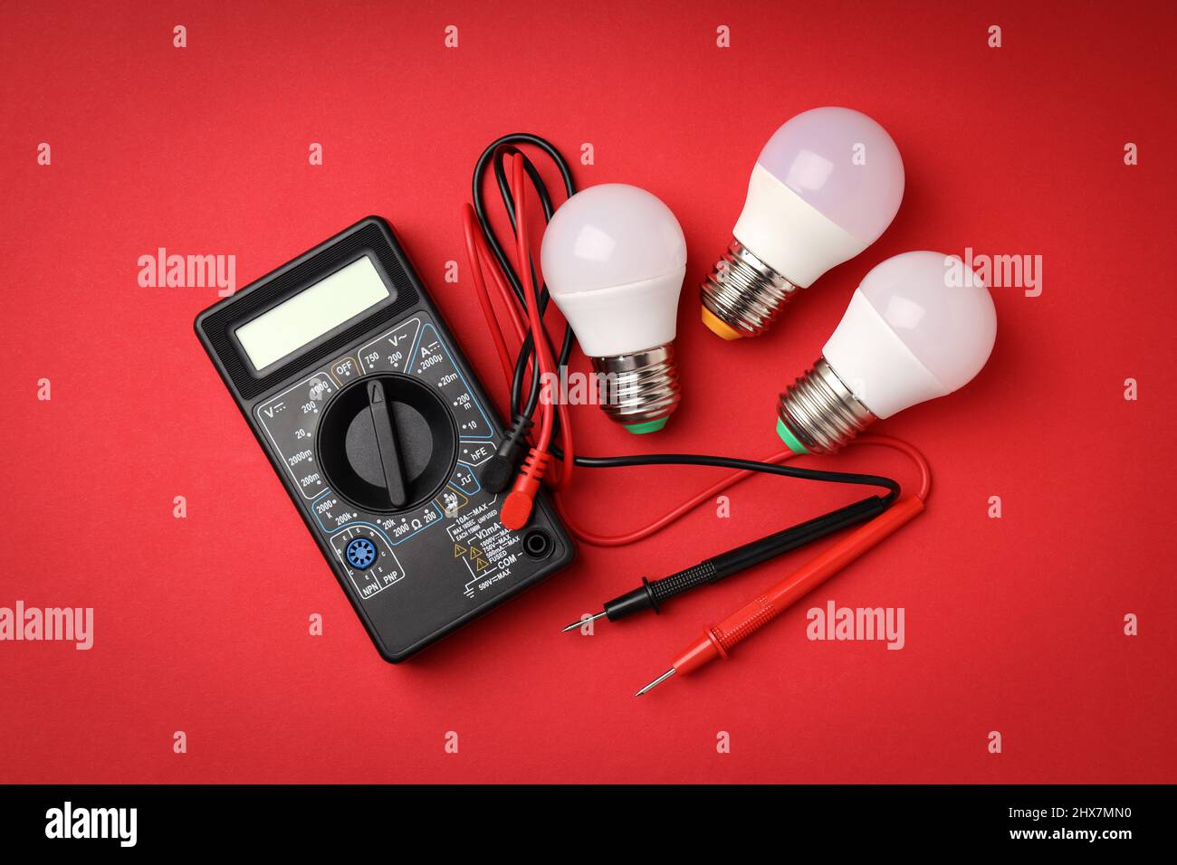 Multimeter and energy saving bulbs on red background Stock Photo