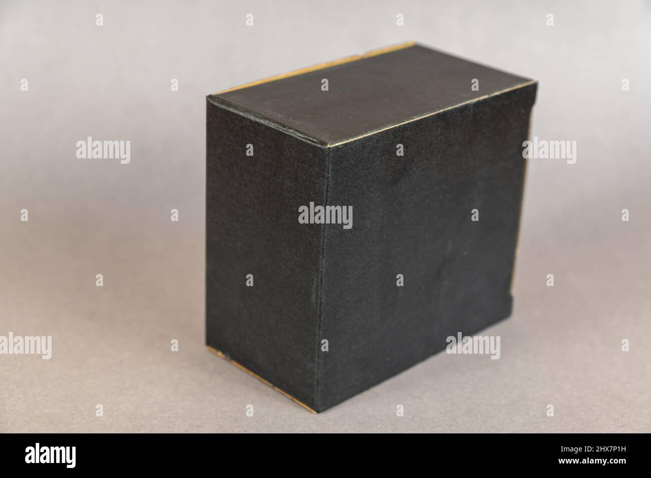 Rectangular black box on a gray background. Closed cardboard package with correct geometric shape. Stock Photo