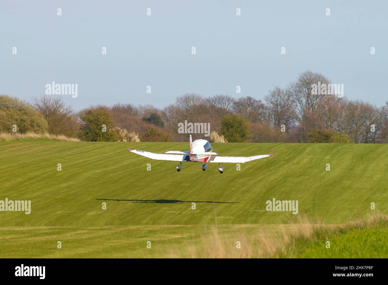 Pierre Robin DR400 Regent light plane taking off from undulating grass runway at Great Oakley airfield, Essex, UK. Private flying in countryside Stock Photo