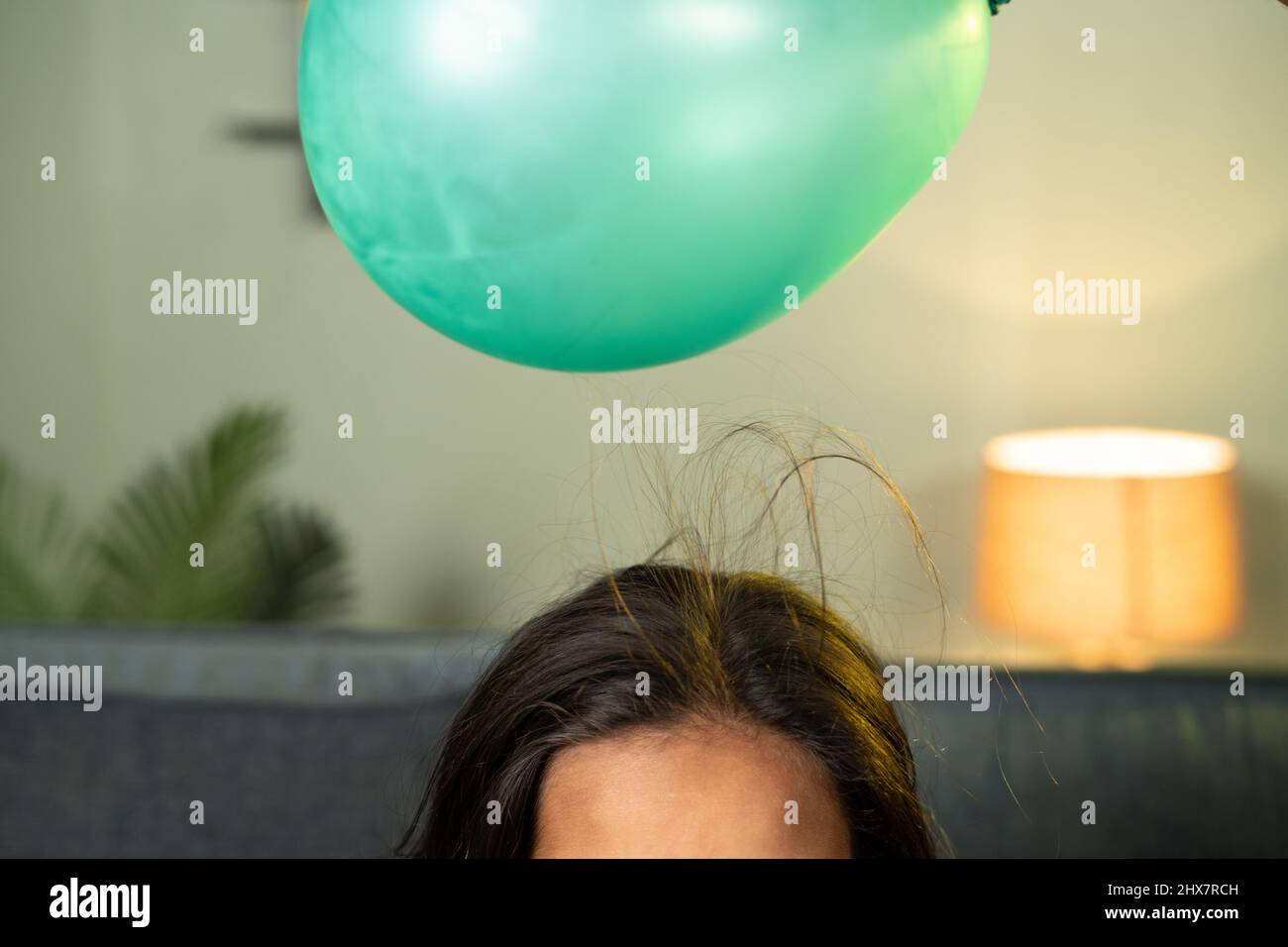 close up shoto of kids playing by placing balloon to attracting hair - conept of static cling home science experiment and learning. Stock Photo