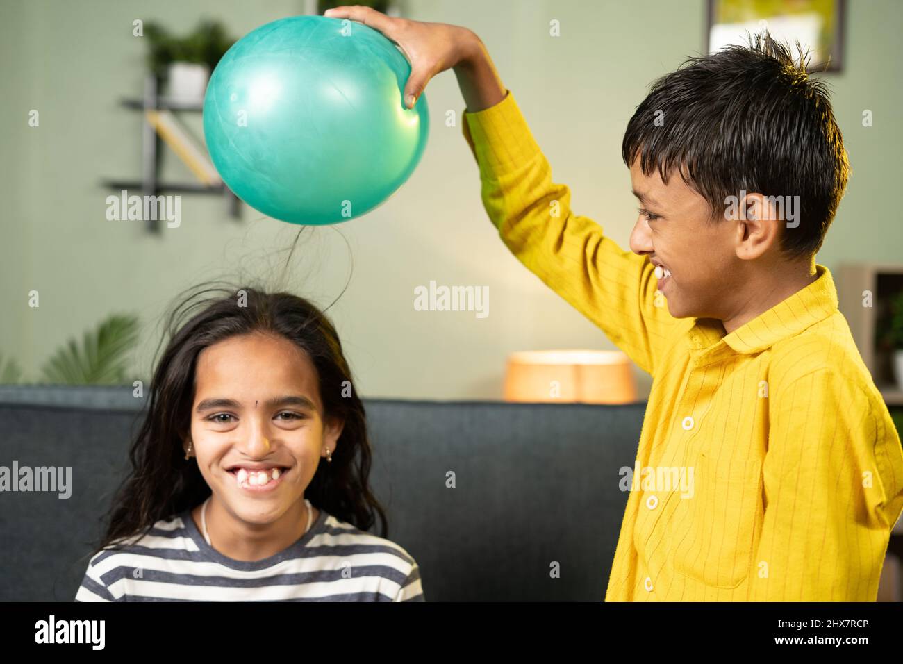 Focus on boy, Kids enjoys static cling experiment by playing while rubbing ballon to hair and hairs attracted to ballon - conept of excitement and Stock Photo