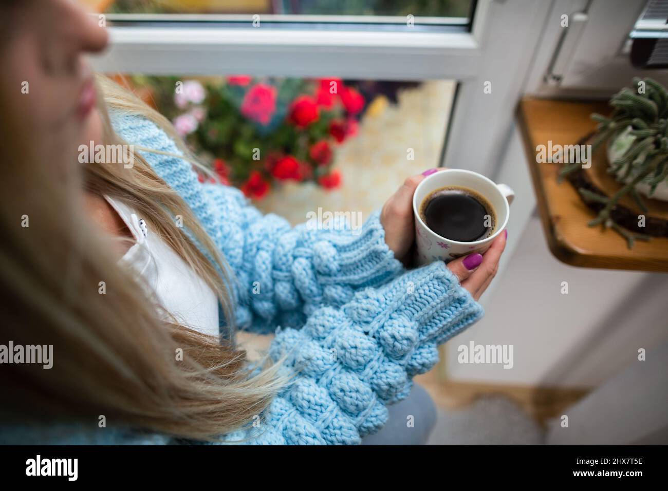 A woman warms her frozen hands against a mug of hot coffee. Stock Photo