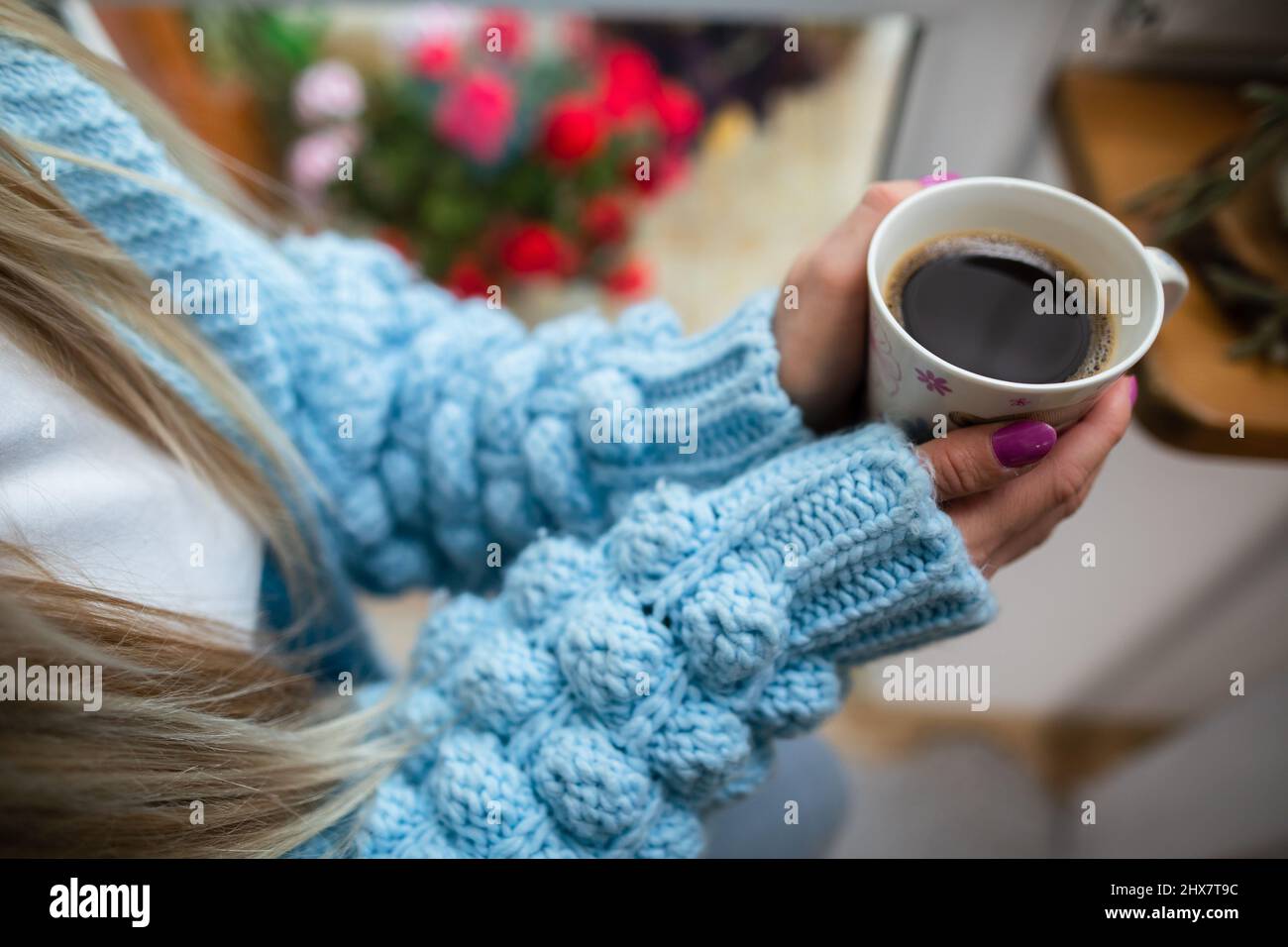 A woman warms her frozen hands against a mug of hot coffee. Stock Photo