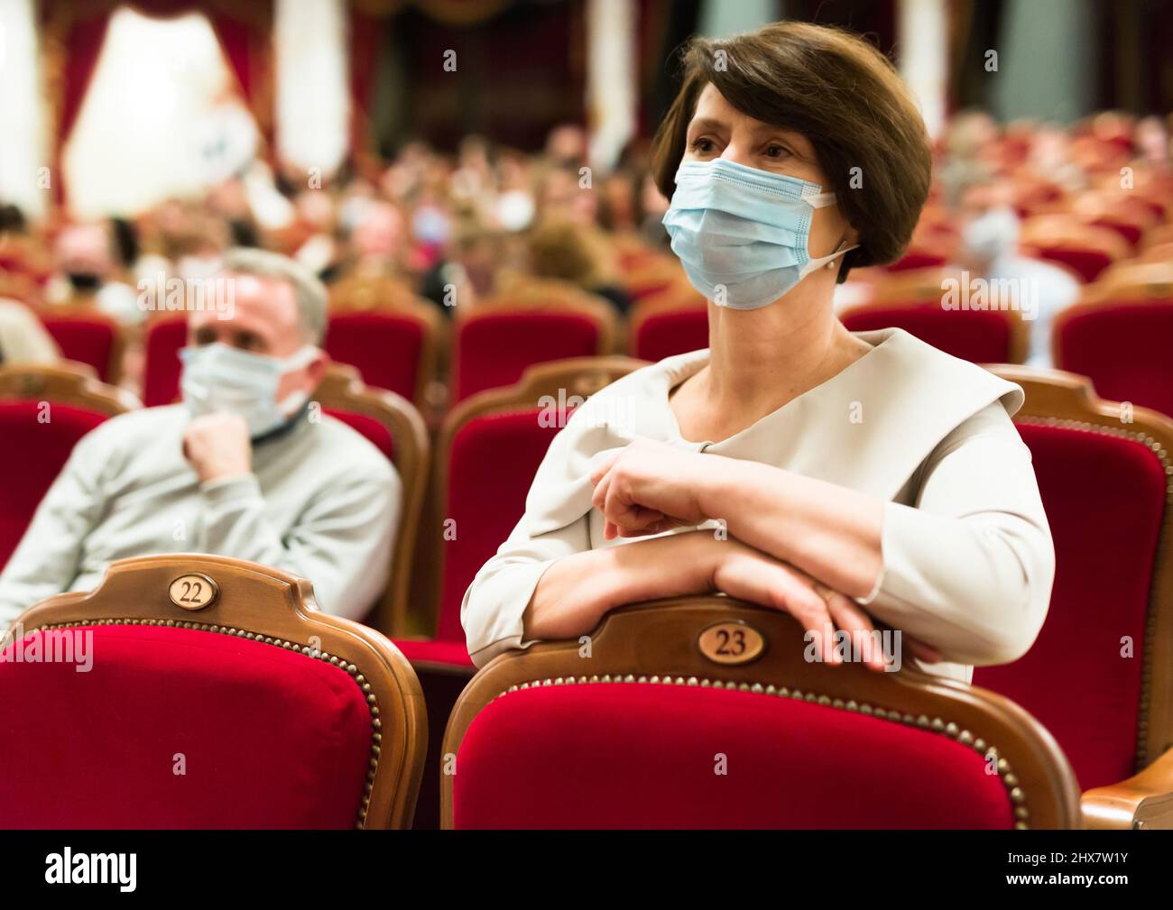 mature woman in antivirus mask watching play in the theater Stock Photo