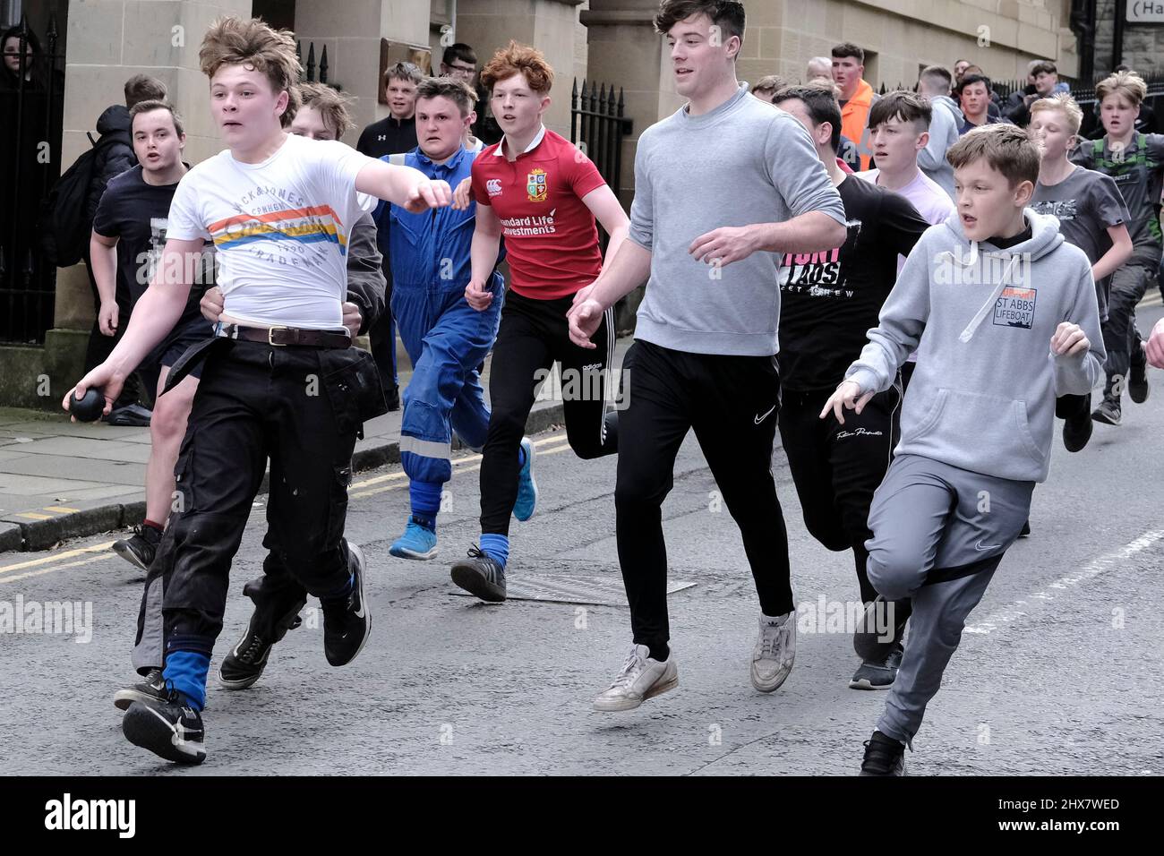 Jedburgh, Thursday 10 March 2022. An unidentified youth with 'Ba' in hand is challenged by others for the 'Schule Ba' the first to be 'hailed' at the start of the annual 'Fastern Eve Handba' event in Jedburgh's High Street in the Scottish Borders on March 10, 2022 in Jedburgh, Scotland. The annual event, which started in the 1700's, takes place today and involves two teams, the Uppies (residents from the higher part of Jedburgh) and the Doonies (residents from the lower part of Jedburgh) getting the ball to either the top or bottom of the town. The ball, which is made of leather, stuffed with Stock Photo