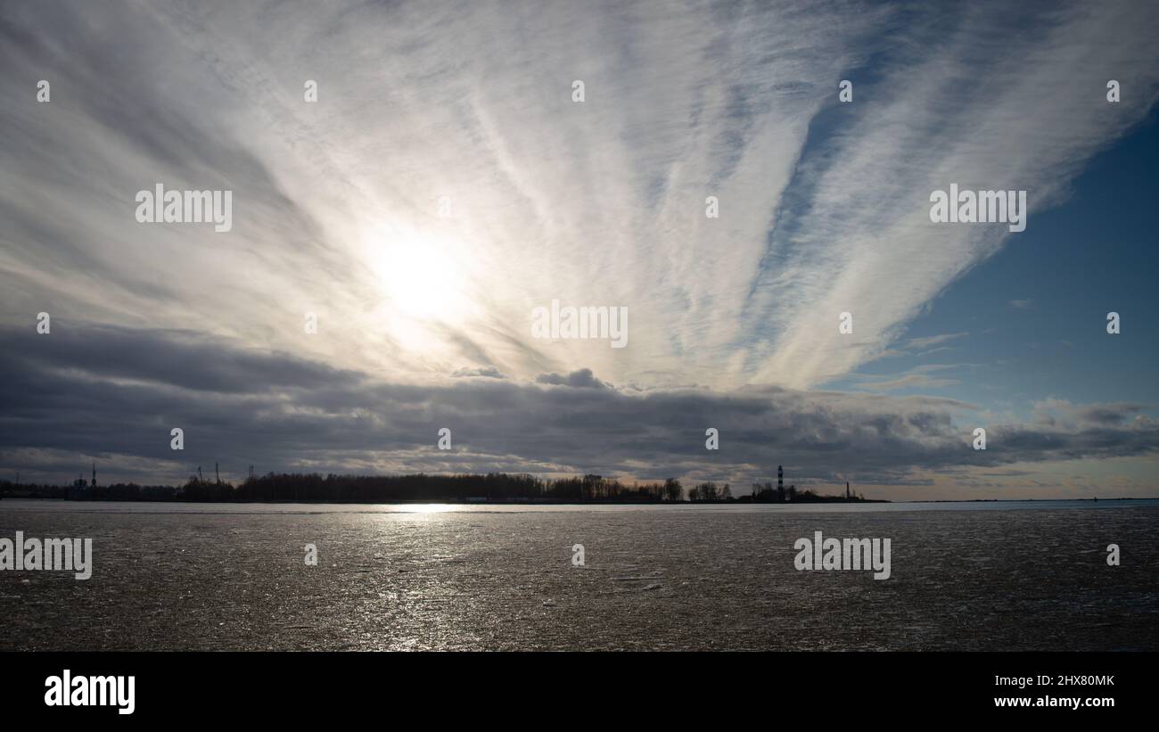 Sunset shining through heavy chemtrail. Seascape at sunset in winter Stock Photo