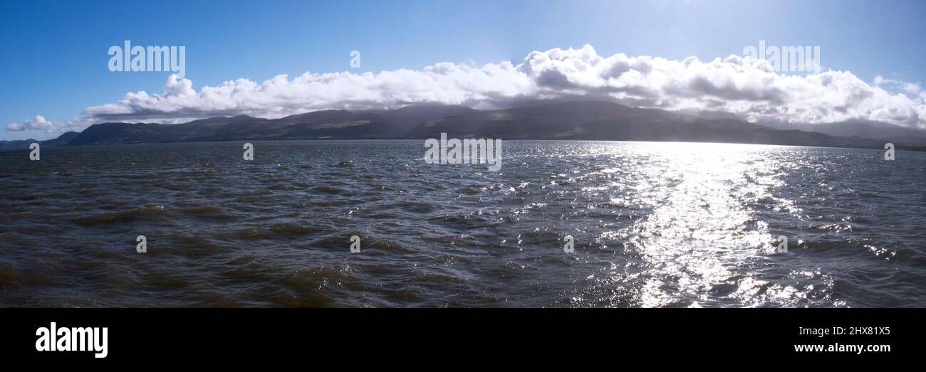 The view across the Menai Straights from Beaumaris on Anglesey. This narrow body of water of fast tidal currents looks onto the peaks of Snowdonia Nat Stock Photo
