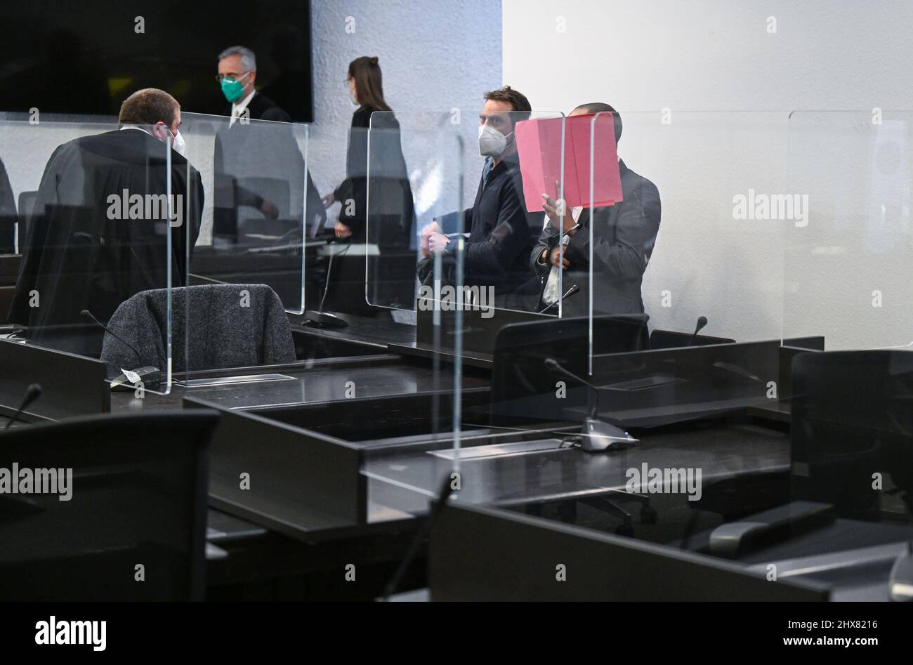 Stuttgart, Germany. 10th Mar, 2022. A defendant holds a file cover in front of his face to shield himself from the cameras before the start of his trial in the courtroom. The man, in a state of incapacitation, allegedly tried to run over three pedestrians, including a young child, with his car on a sidewalk in Altbach last September. Two people were hit and seriously injured. Credit: Bernd Weißbrod/dpa/Alamy Live News Stock Photo