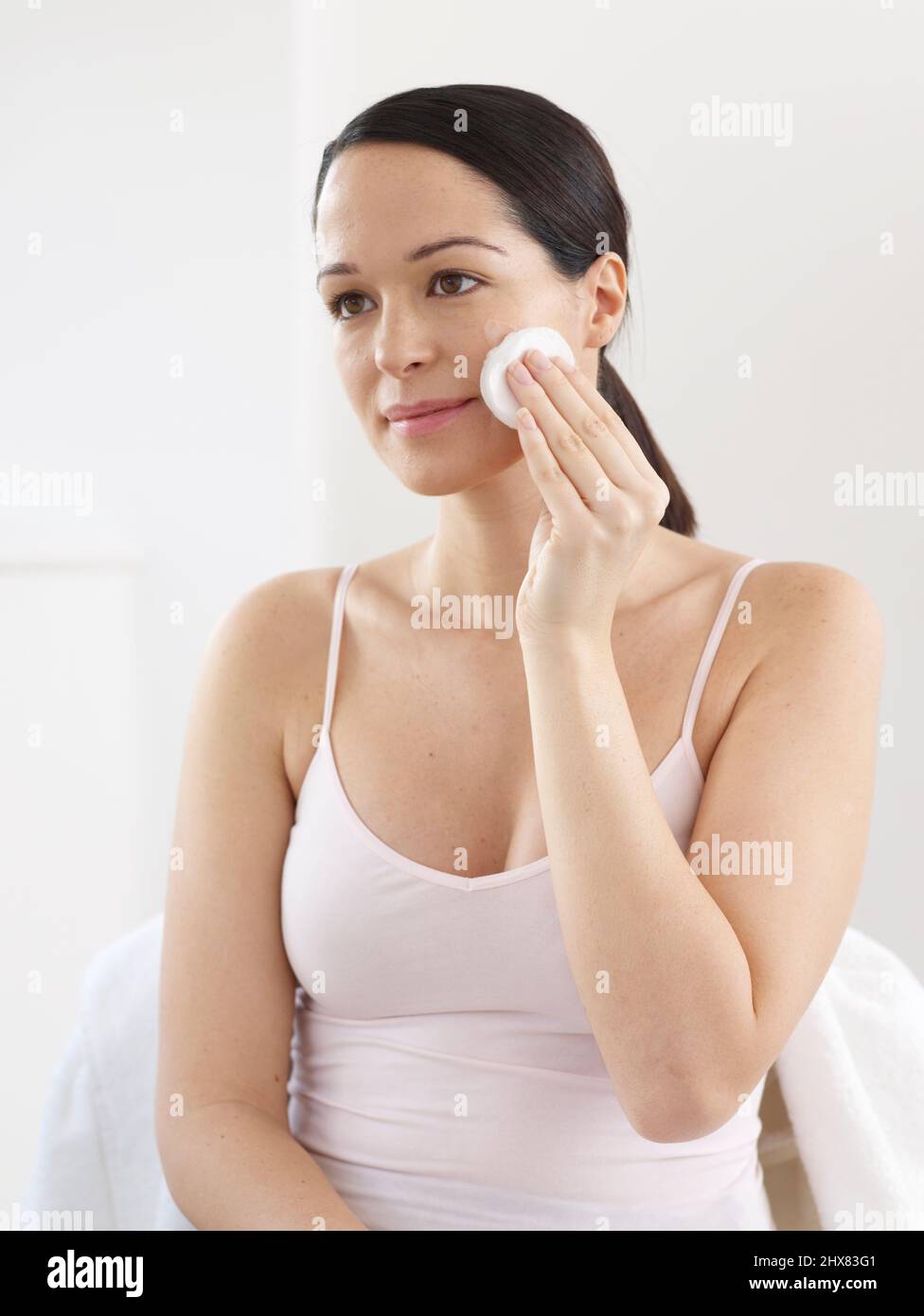 Woman cleansing her face using a cotton pad Stock Photo