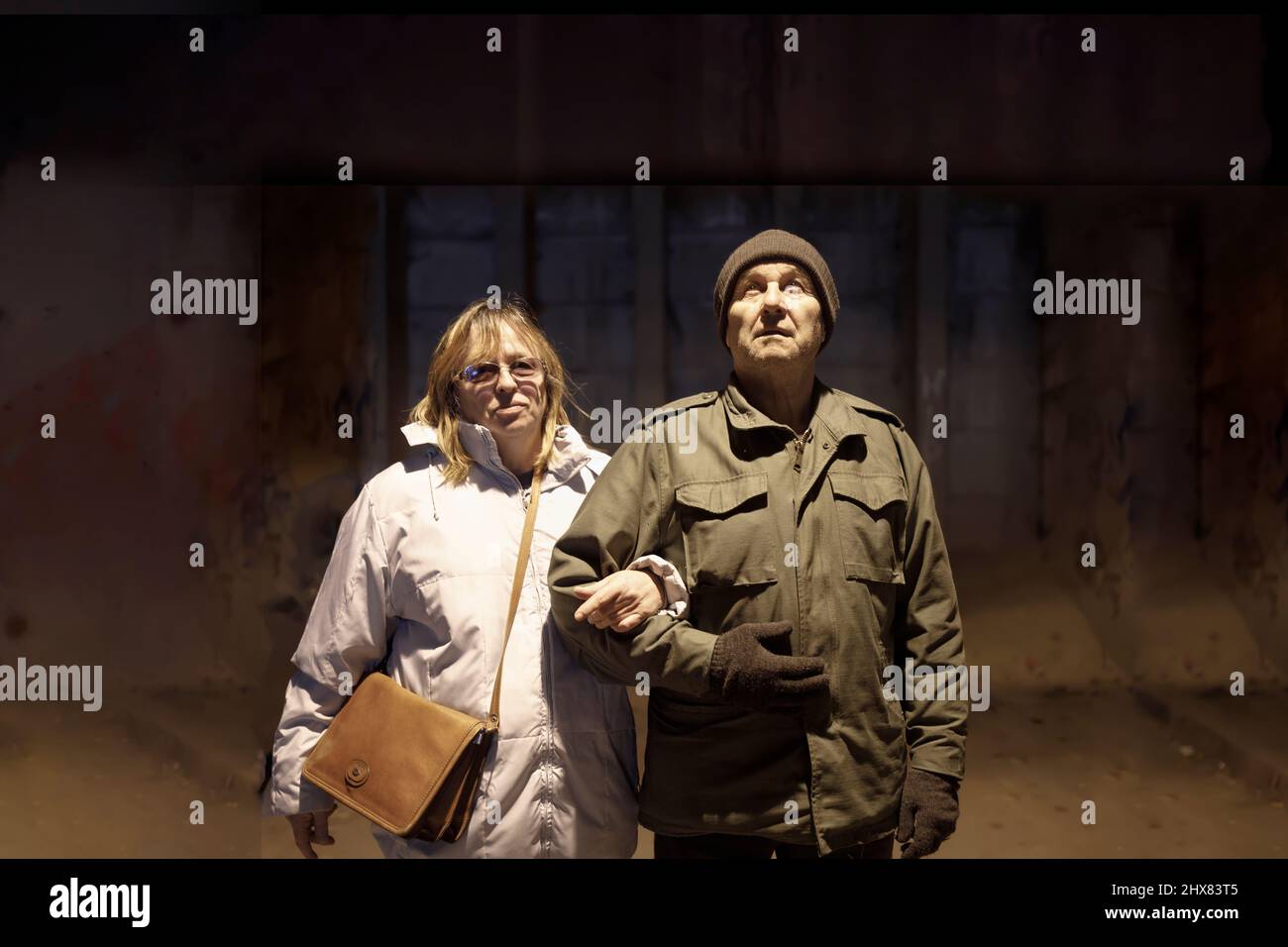 Elderly wife and husband standing together in a nuclear shelter Stock Photo