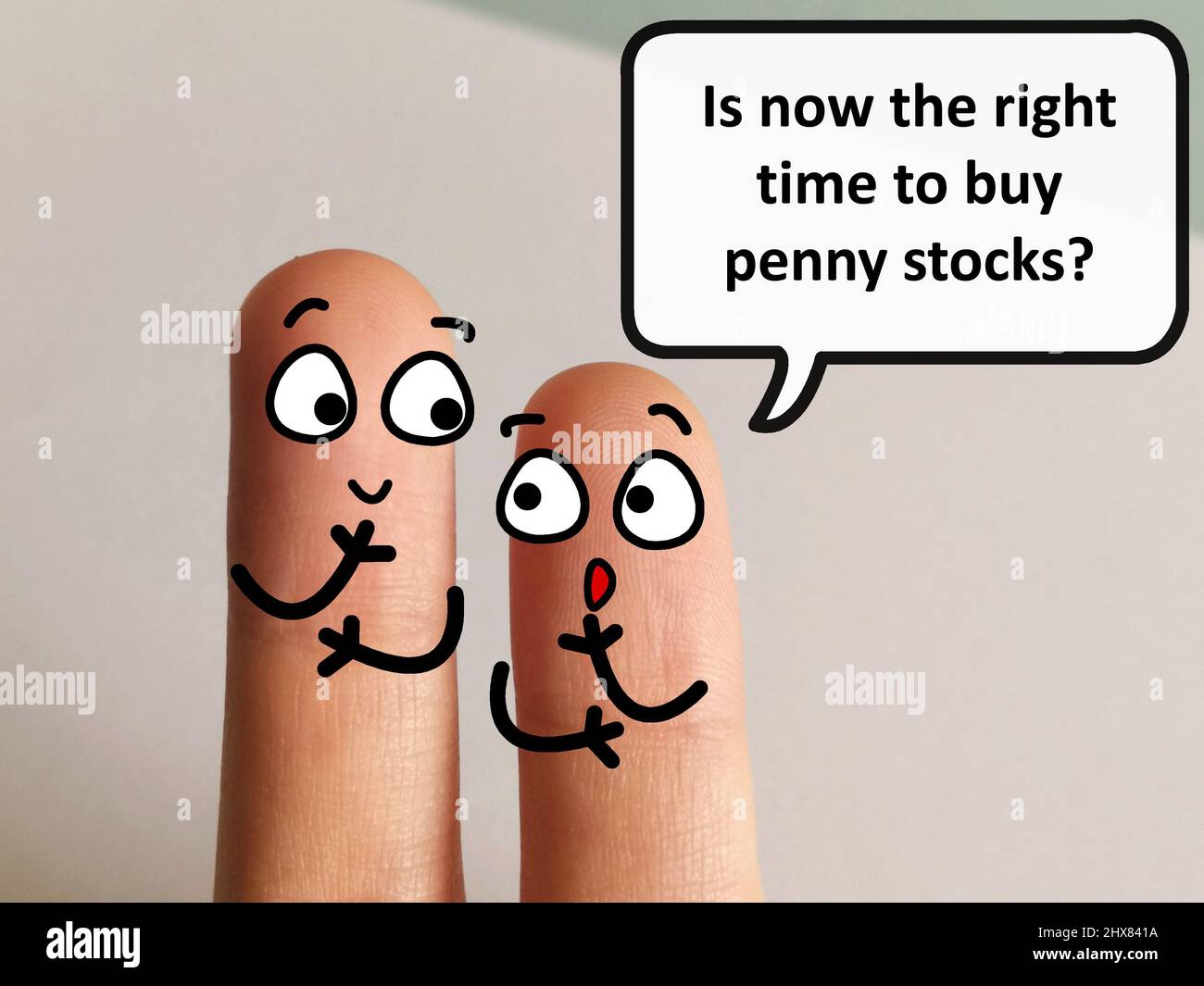 Two fingers are decorated as two person. They are discussing if it is the right time to buy penny stocks. Stock Photo