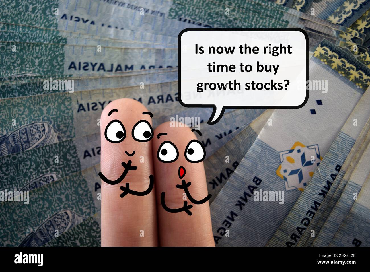 Two fingers are decorated as two person. They are discussing if it is the right time to buy growth stocks. Stock Photo