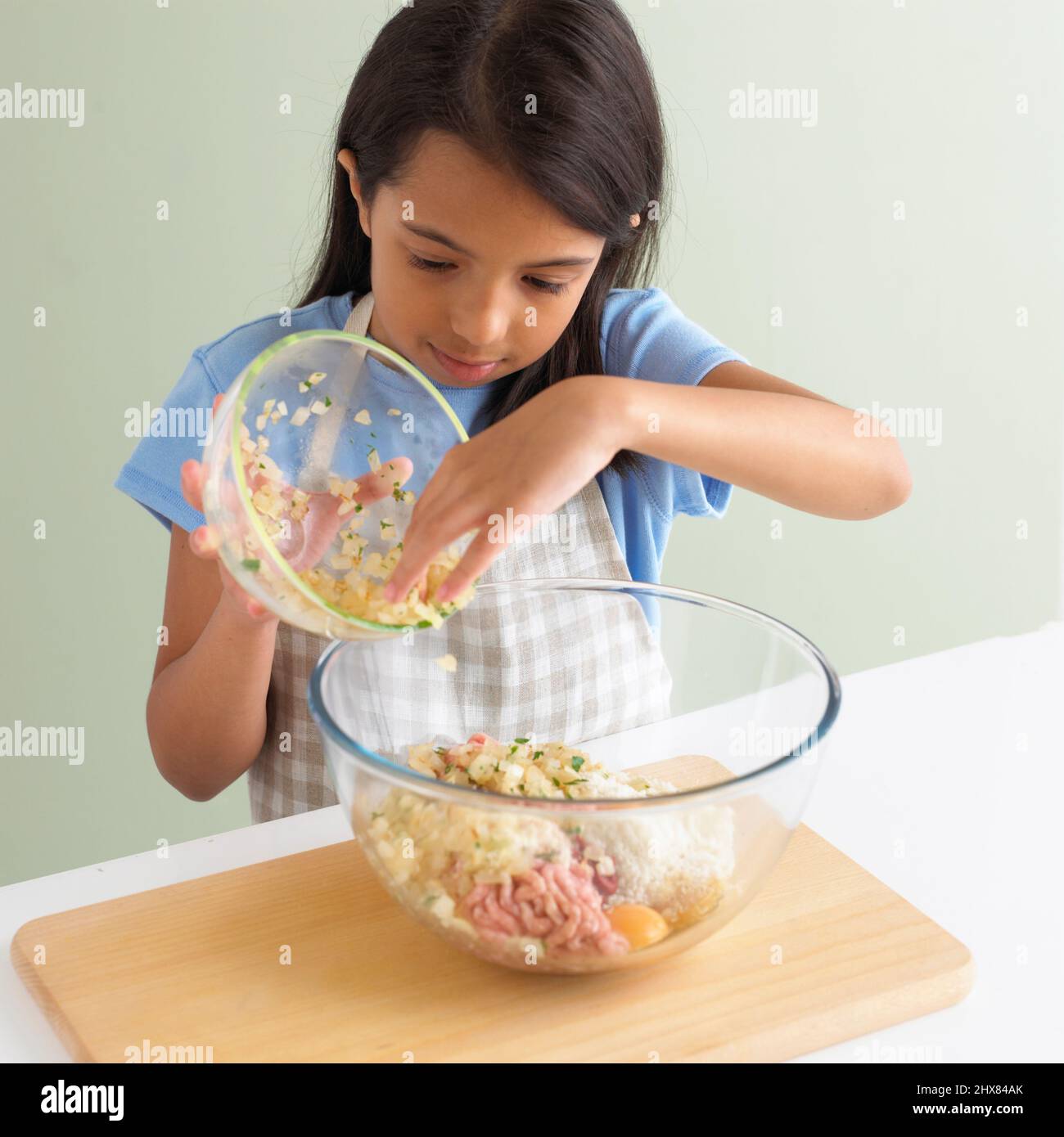 https://c8.alamy.com/comp/2HX84AK/girl-emptying-chopped-onion-into-raw-ingredients-in-large-glass-mixing-bowl-close-up-2HX84AK.jpg