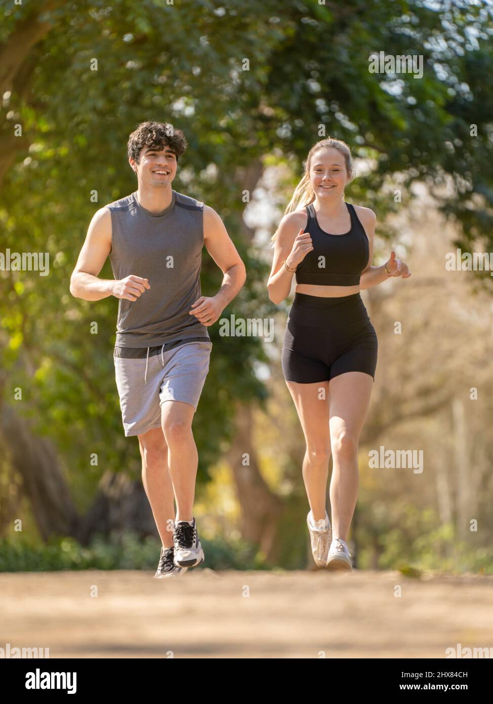 Young couple doing sports running on a park path and smiling Stock Photo