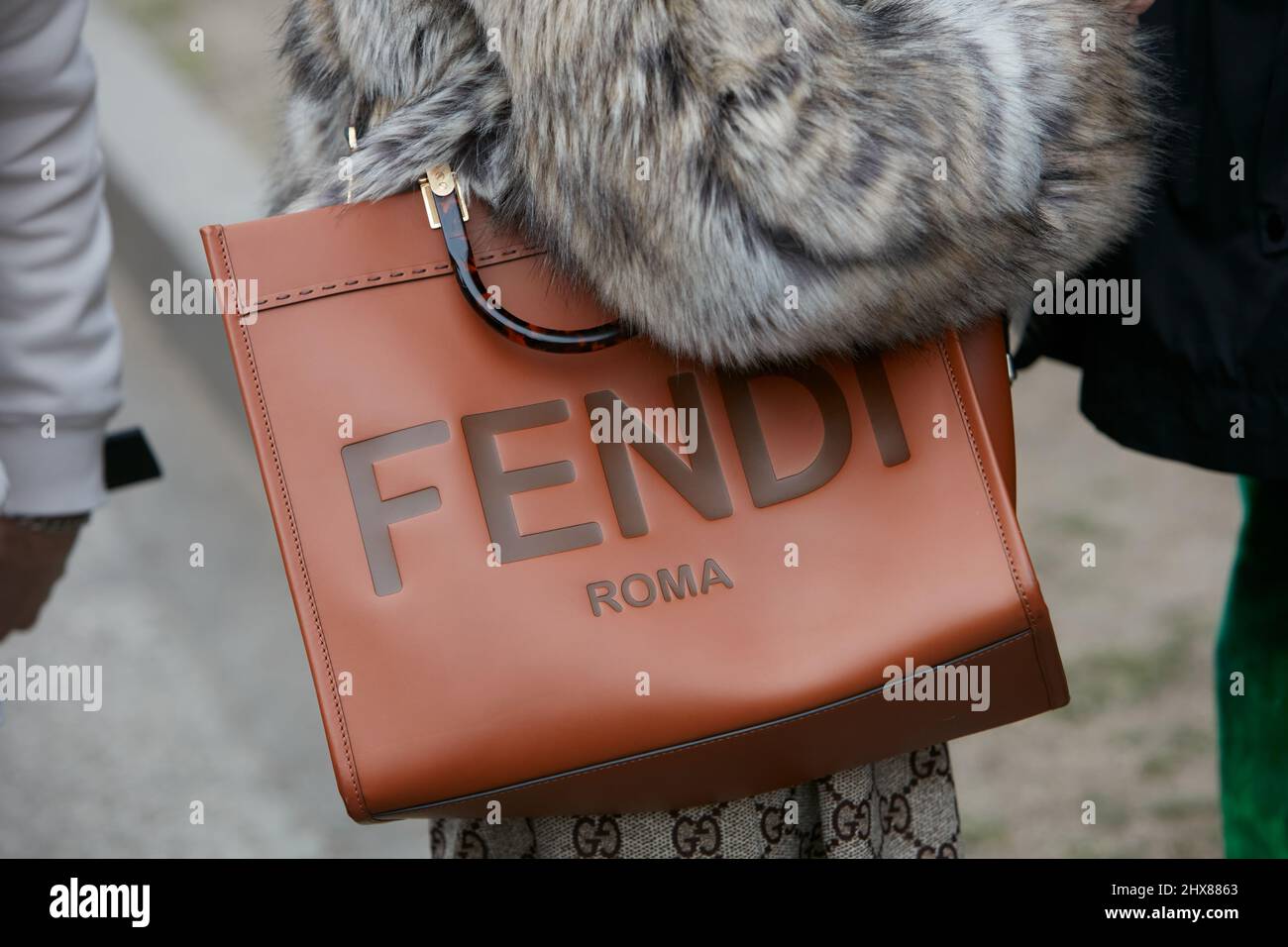 MILAN, ITALY - FEBRUARY 24, 2022: Woman with brown leather Fendi bag and fur coat before Emporio Armani fashion show, Milan Fashion Week street style Stock Photo