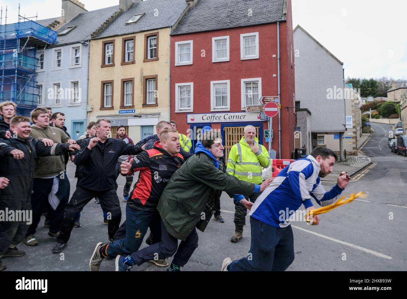 Jedburgh, Thursday 10 March 2022. A man runs with the Ba after catching the “hailed” “Ba” during the annual 'Fastern Eve Handba' event in Jedburgh's High Street in the Scottish Borders on March 10, 2022 in Jedburgh, Scotland. The annual event, which started in the 1700's, takes place today and involves two teams, the Uppies (residents from the higher part of Jedburgh) and the Doonies (residents from the lower part of Jedburgh) getting the ball to either the top or bottom of the town. The ball, which is made of leather, stuffed with straw and decorated with ribbons is thrown into the crowd to b Stock Photo