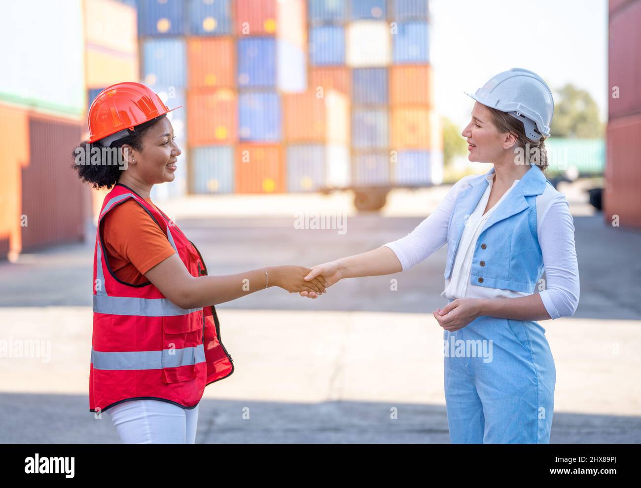 Warehouse business. A African american Woman foreman and a CEO woman in suit shake hands and conclude a job for transport and logistics after  Success Stock Photo