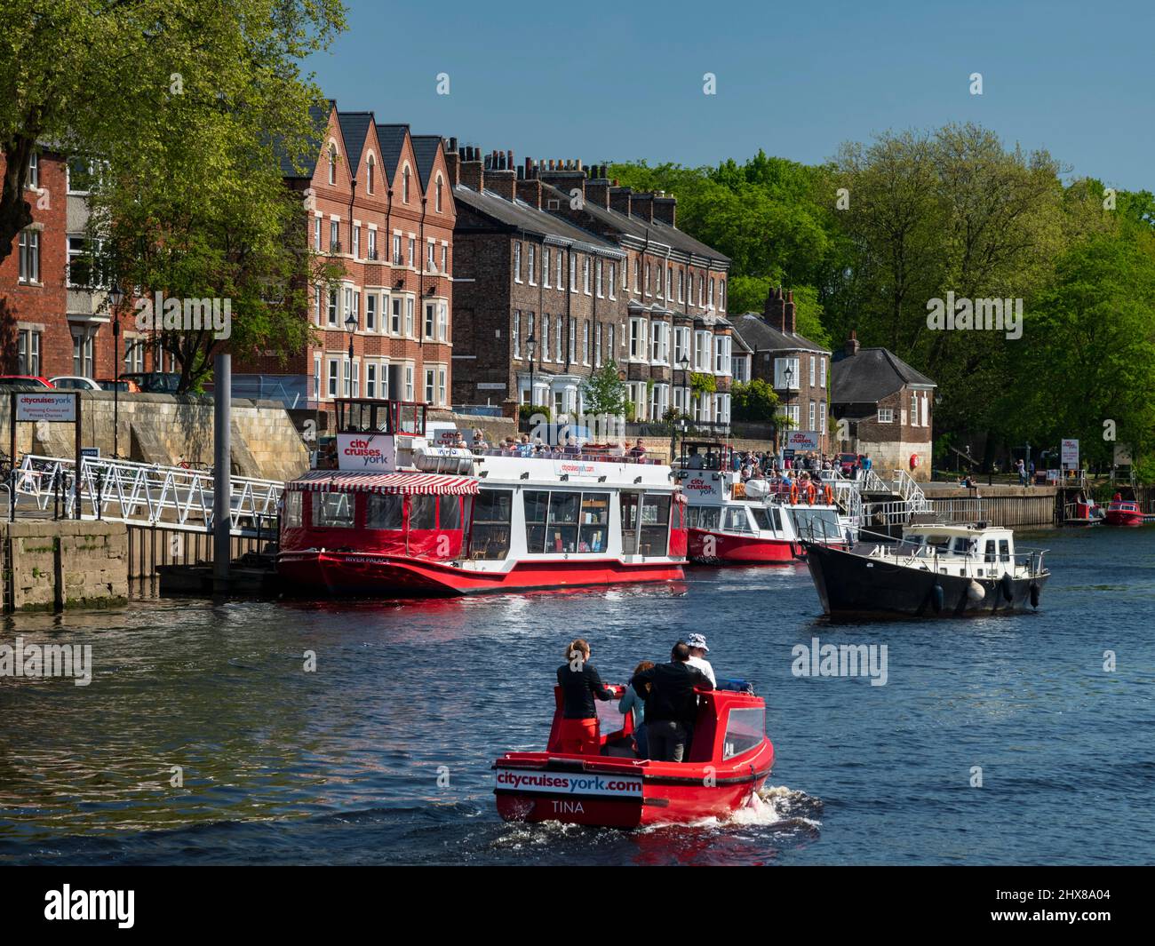 City Cruises boats & motorboat sailing on water - busy sunny picturesque River Ouse quayside moorings, King's Staith, York, North Yorkshire, England. Stock Photo