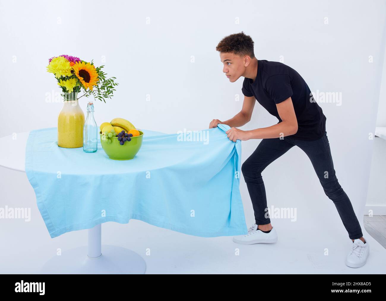 Boy, 12, performing the table-cloth trick Stock Photo
