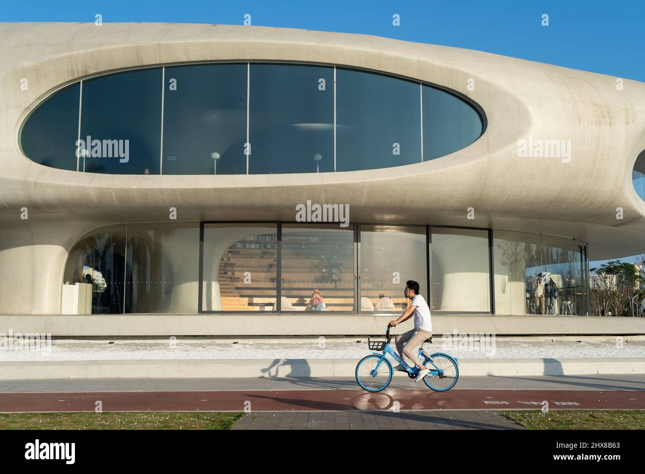 landscape photo of man riding bike across haikou wormhole library Stock Photo