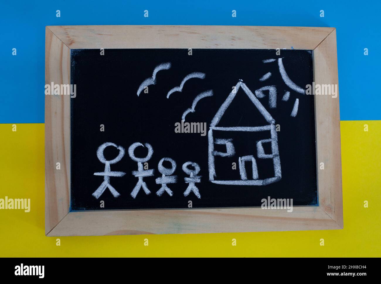 children's drawings on chalkboard with Ukrainian colors depicting the loss and destruction faced by refugees of Russian invasion of Ukraine 2022 Stock Photo