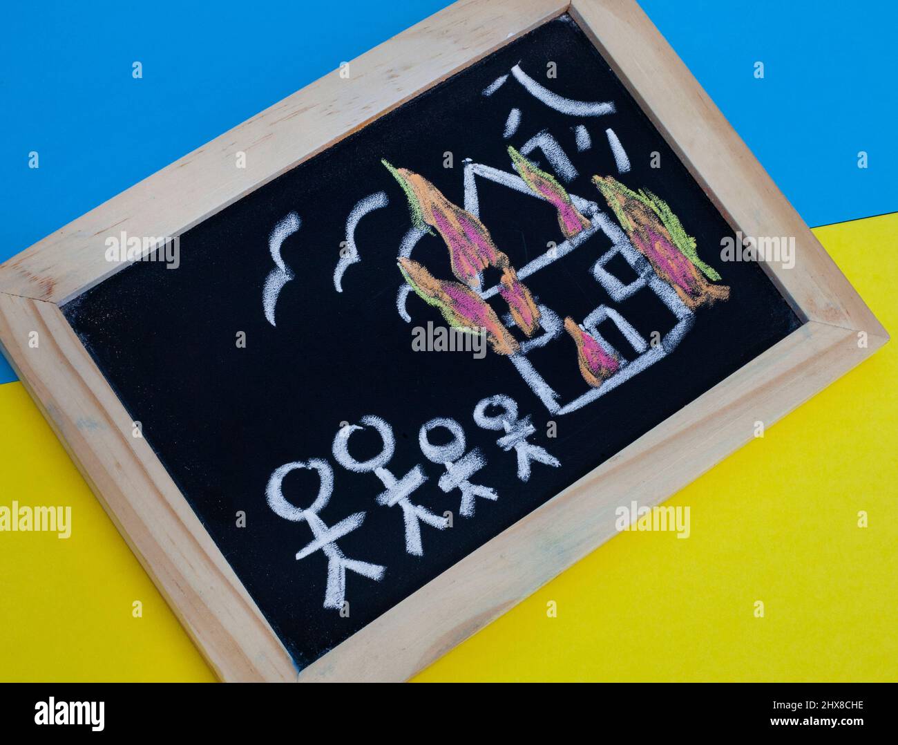 children's drawings on chalkboard with Ukrainian colors depicting the loss and destruction faced by refugees of Russian invasion of Ukraine 2022 Stock Photo