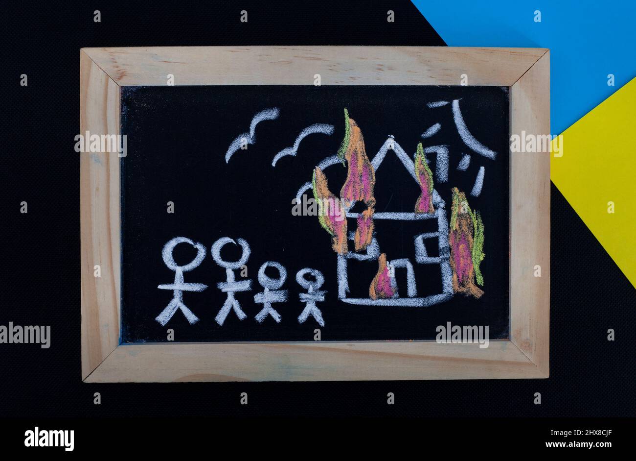 children's drawings on chalkboard with Ukrainian colors depicting the loss and destruction faced by refugees of Russian invasion of Ukraine 2022 Stock Photo