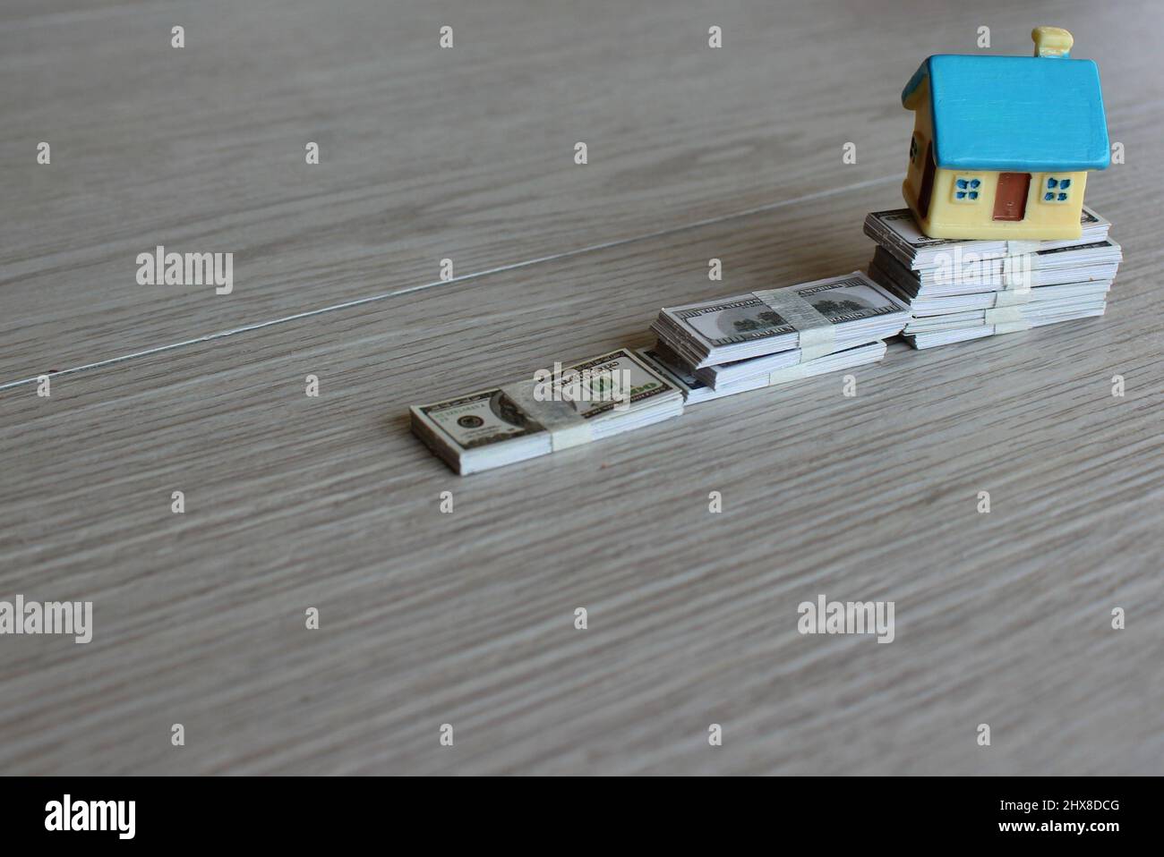 House prices rising, property investment concept. Toy house on top of stack of money. Stock Photo