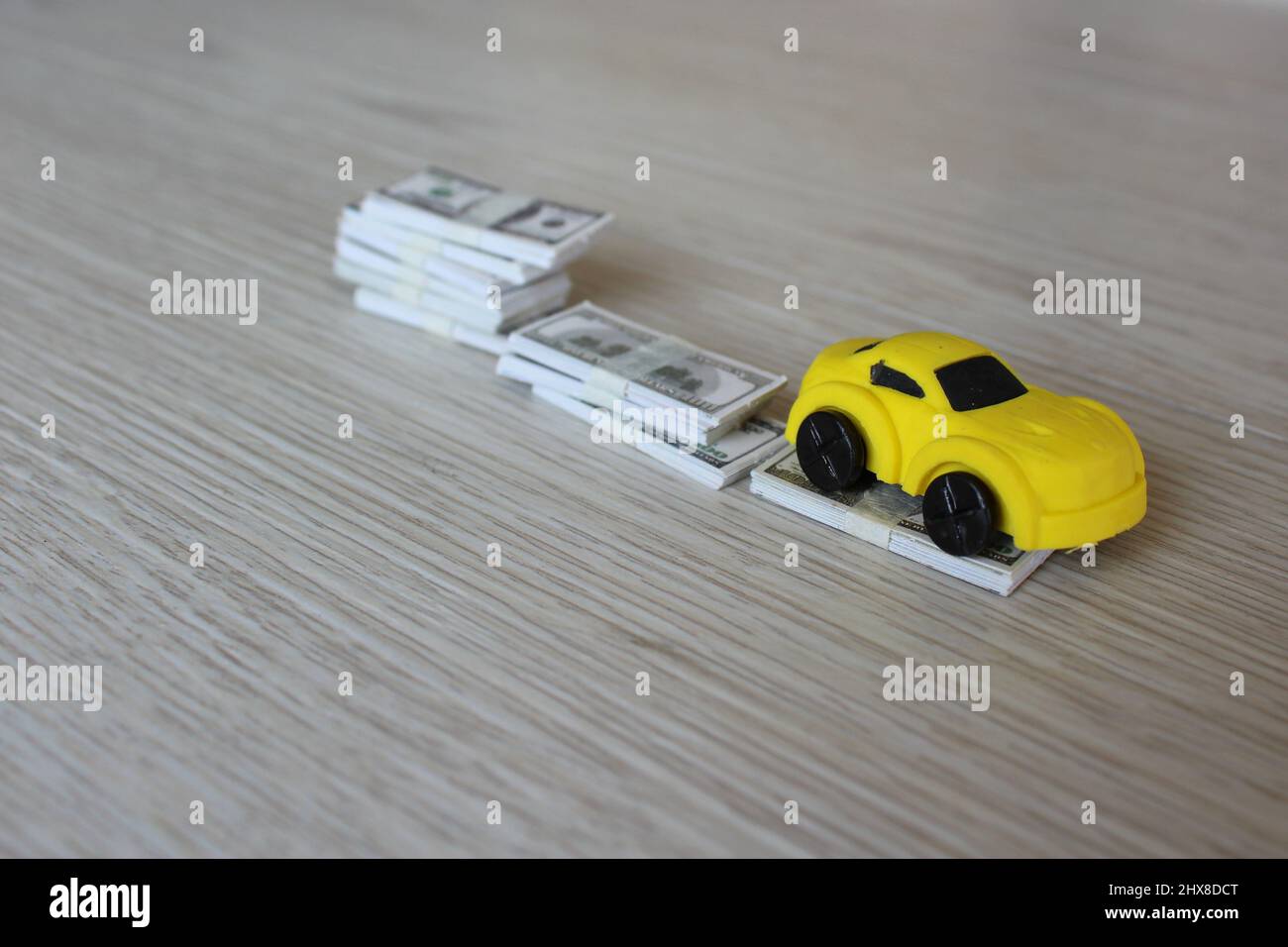 Selective focus image of toy car and stack of money. Car depreciation