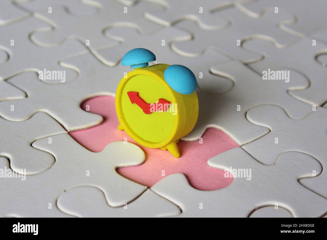 Missing jigsaw puzzle pieces and alarm clock. Time management concept