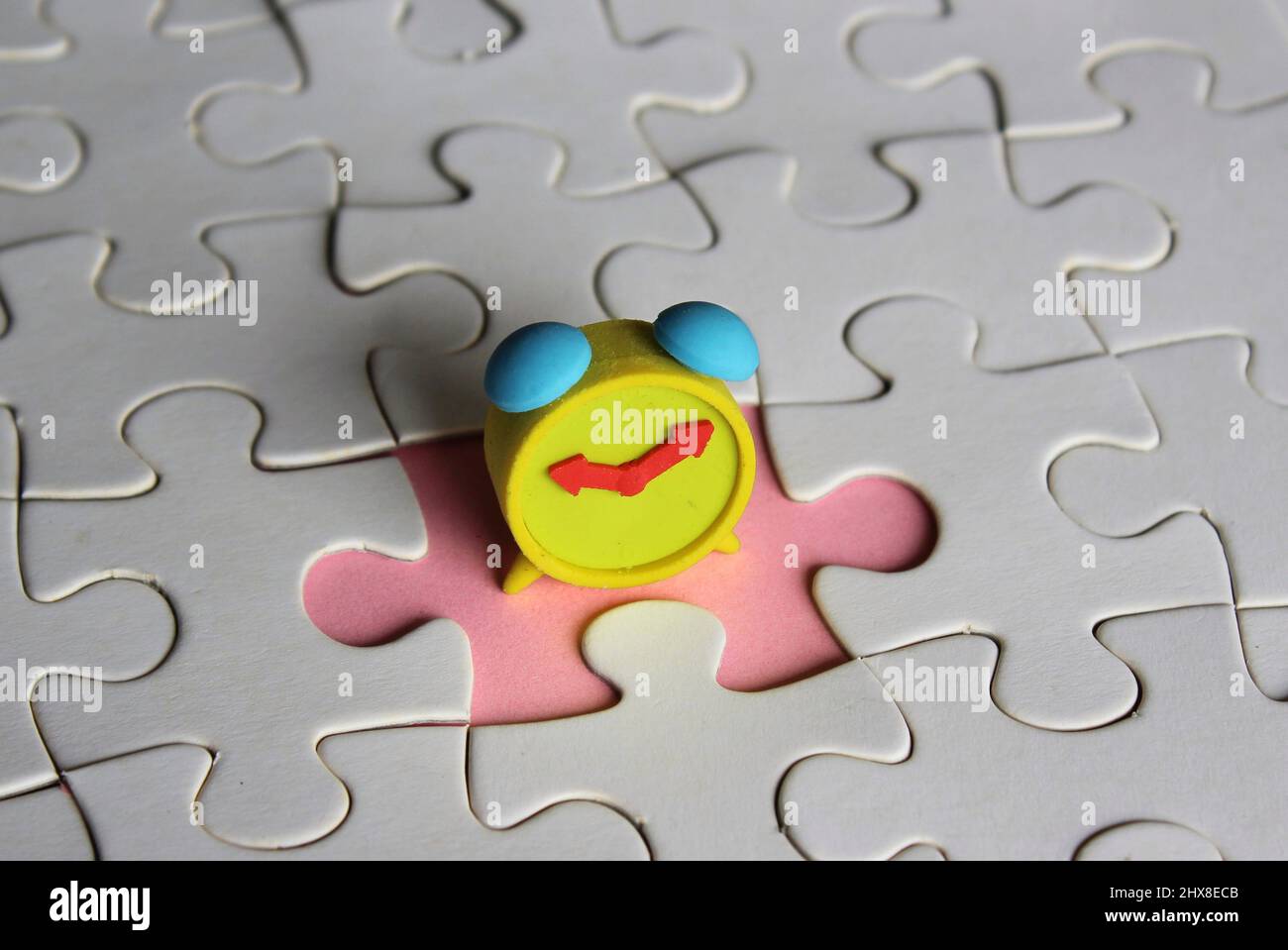 Missing jigsaw puzzle pieces and alarm clock. Time management concept