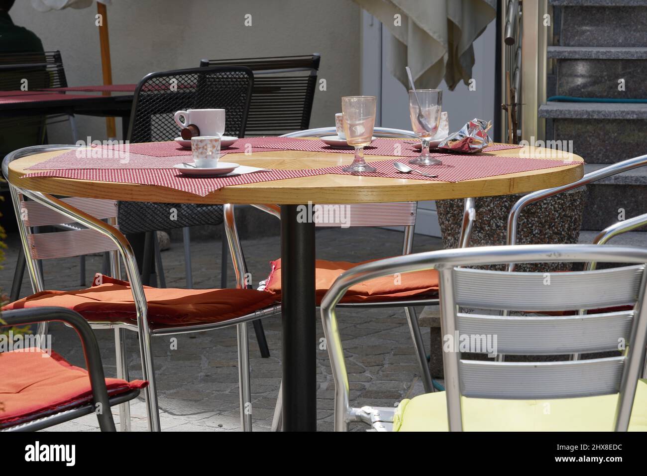 Einsiedeln, Switzerland 06 19 2021: Empty table in a terrace café with cups and glasses on it. There are empty chairs around the table. Stock Photo