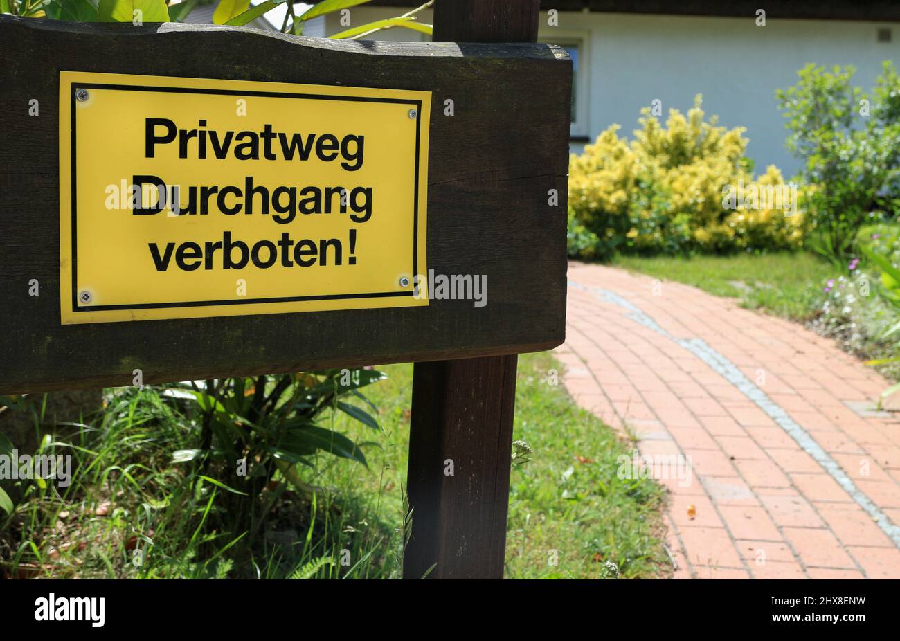 Yellow warning sign with the German text 'Privatweg Durchgang verboten' which translates into 'Private way passage forbidden' in English language Stock Photo