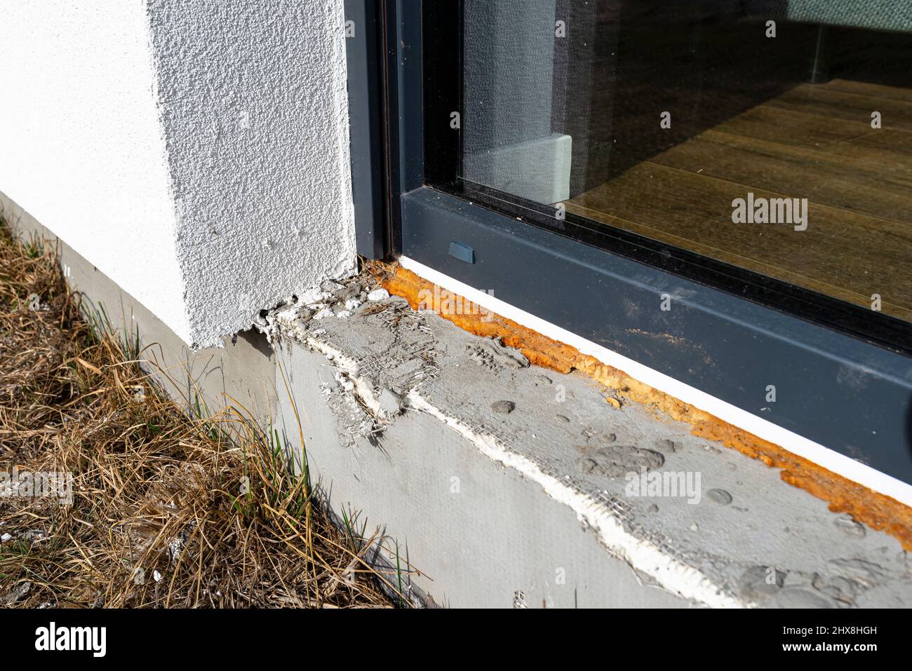 Old yellowed mounting foam under a large terrace window, visible