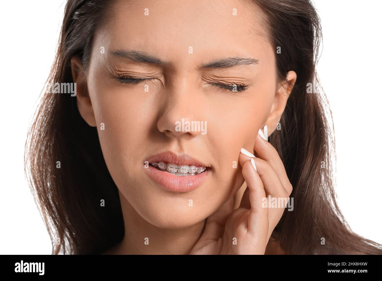 Teenage girl with dental braces suffering from toothache on white