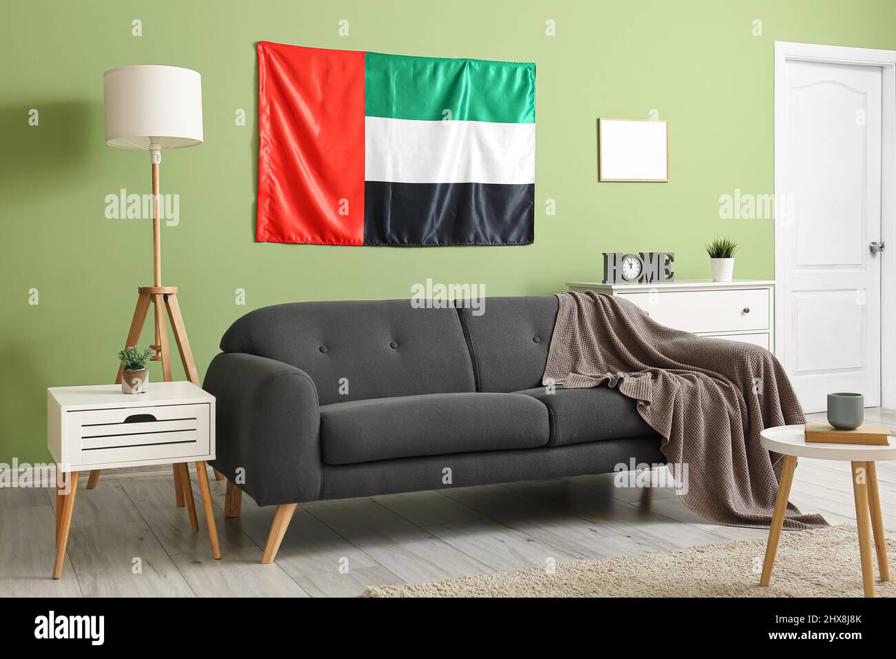 Interior of stylish living room with black sofa, UAE flag and green