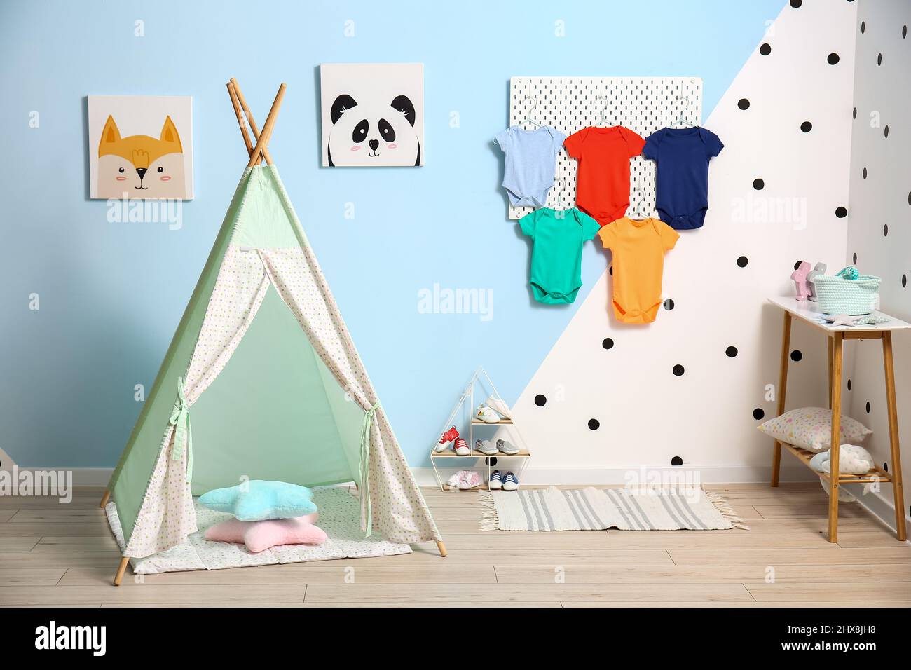 Interior of stylish children's room with pegboard, baby bodysuits and
