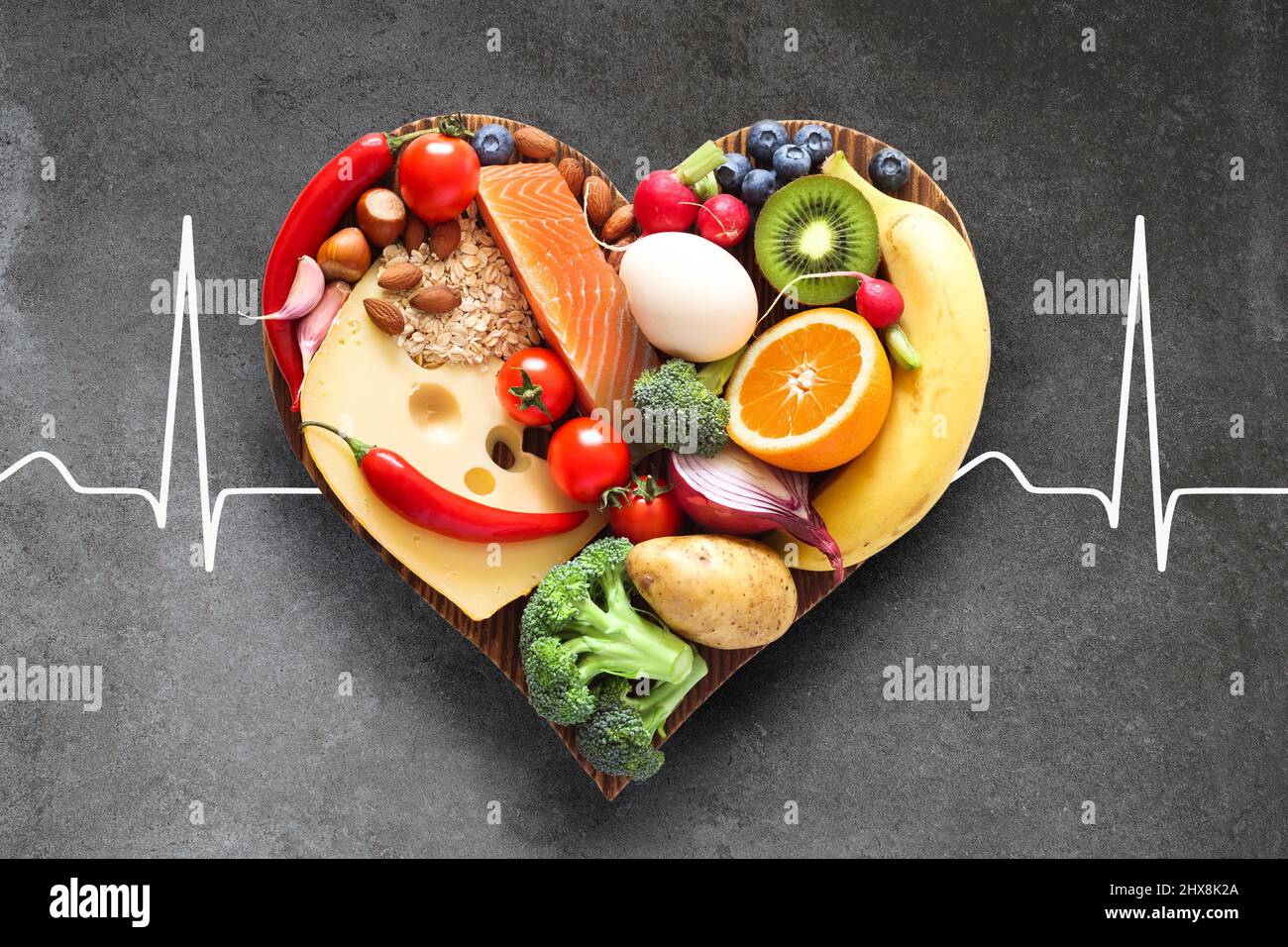 Balanced diet. Healthy food on a heart-shaped wooden cutting board. Stock Photo