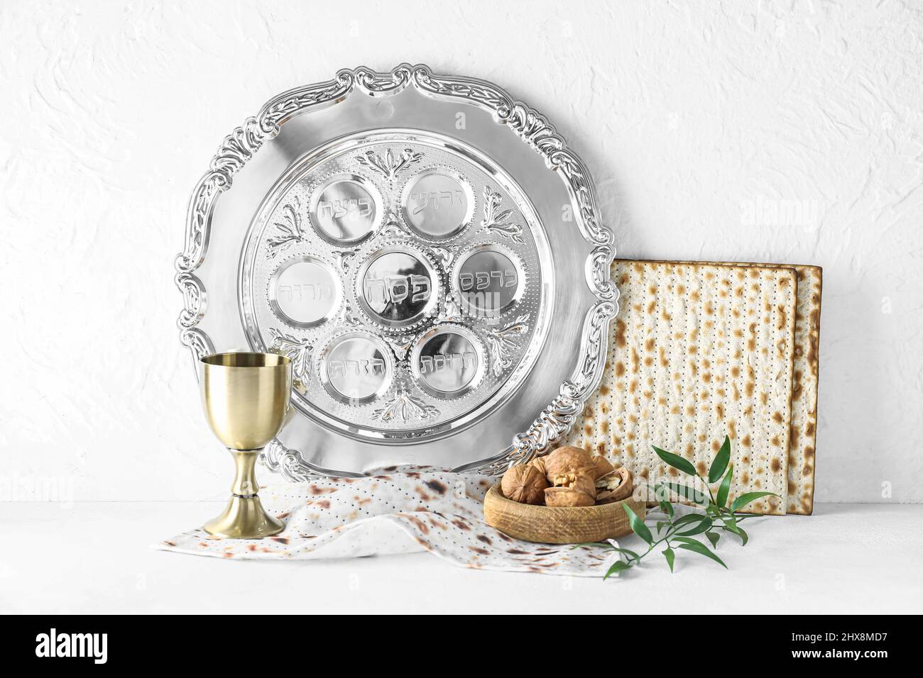 Passover Seder plate with cup of wine, walnuts and matza on white ...