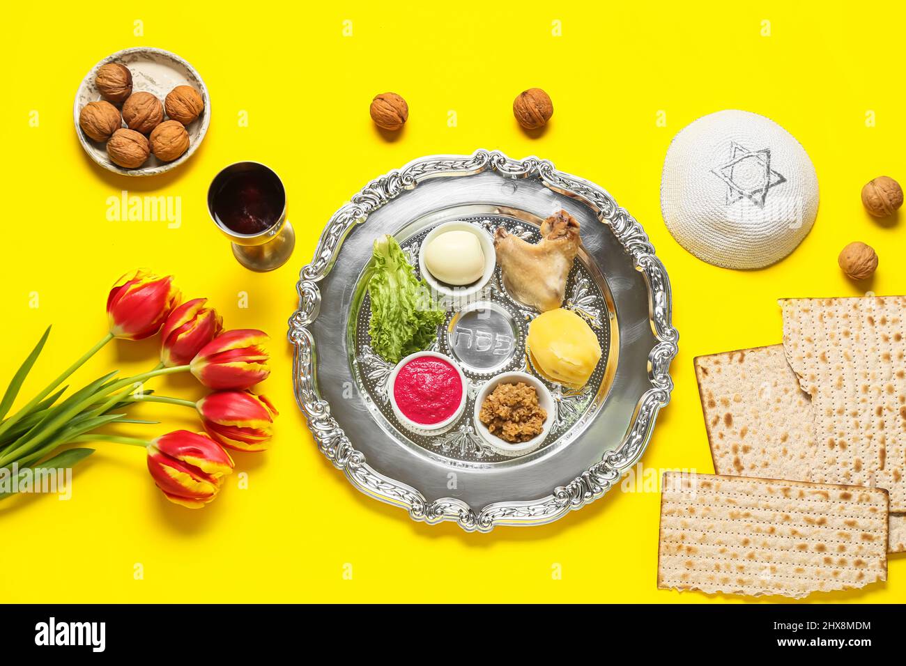 Passover Seder plate with traditional food, flowers and kippah on color ...