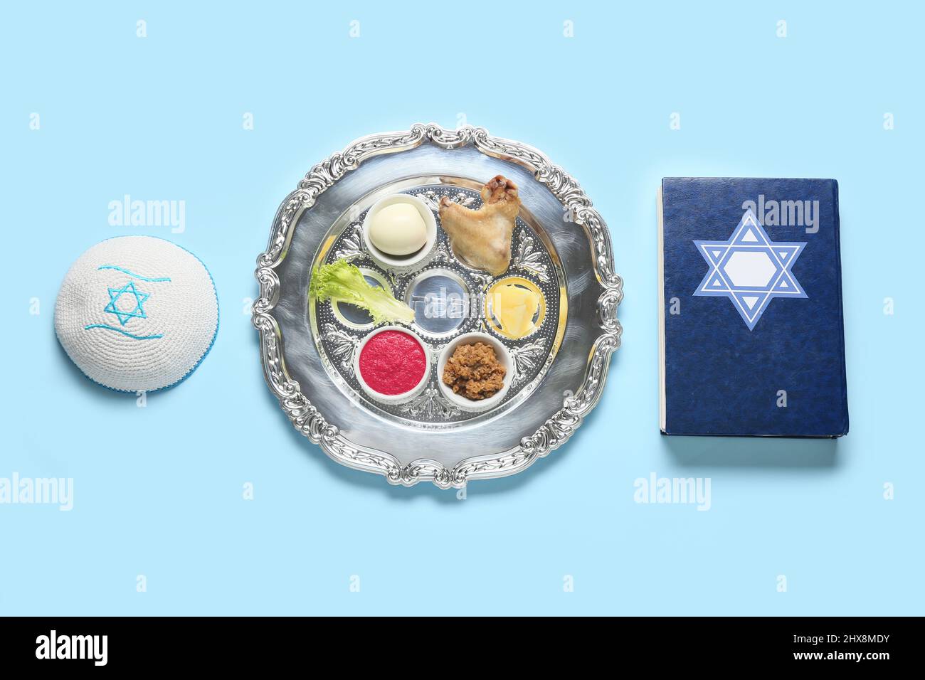 Passover Seder plate with traditional food, kippah and Torah on color ...